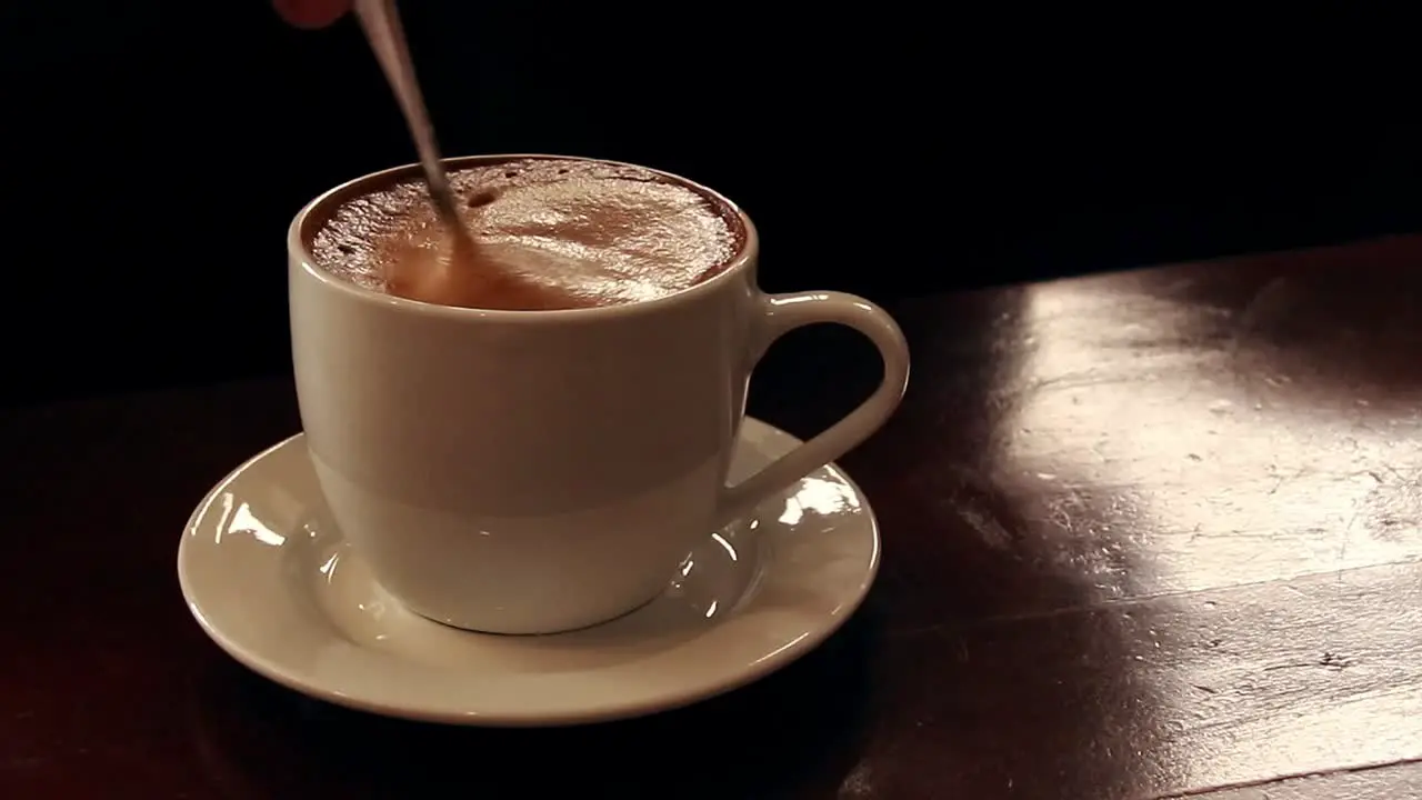 Ambient motion of leisurely stirring a cup of frothy coffee showing the calm and peaceful autumn mood and aesthetic