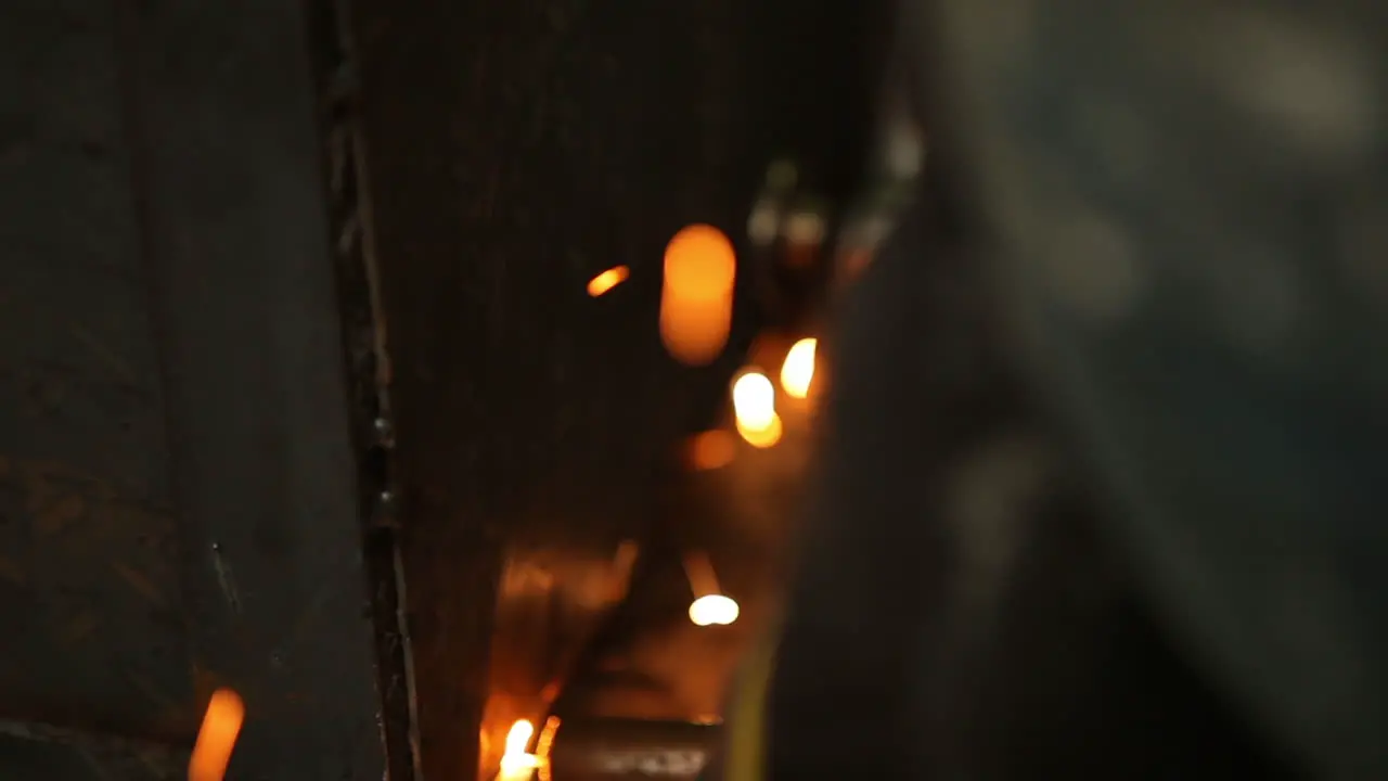 Welder connecting metal sheets and leaving sparks on the factory floor