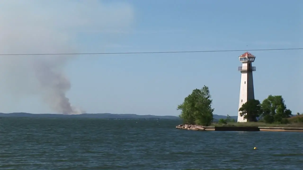 Mediumshot Of A Lighthouse With Smoke Rising On The Horizon