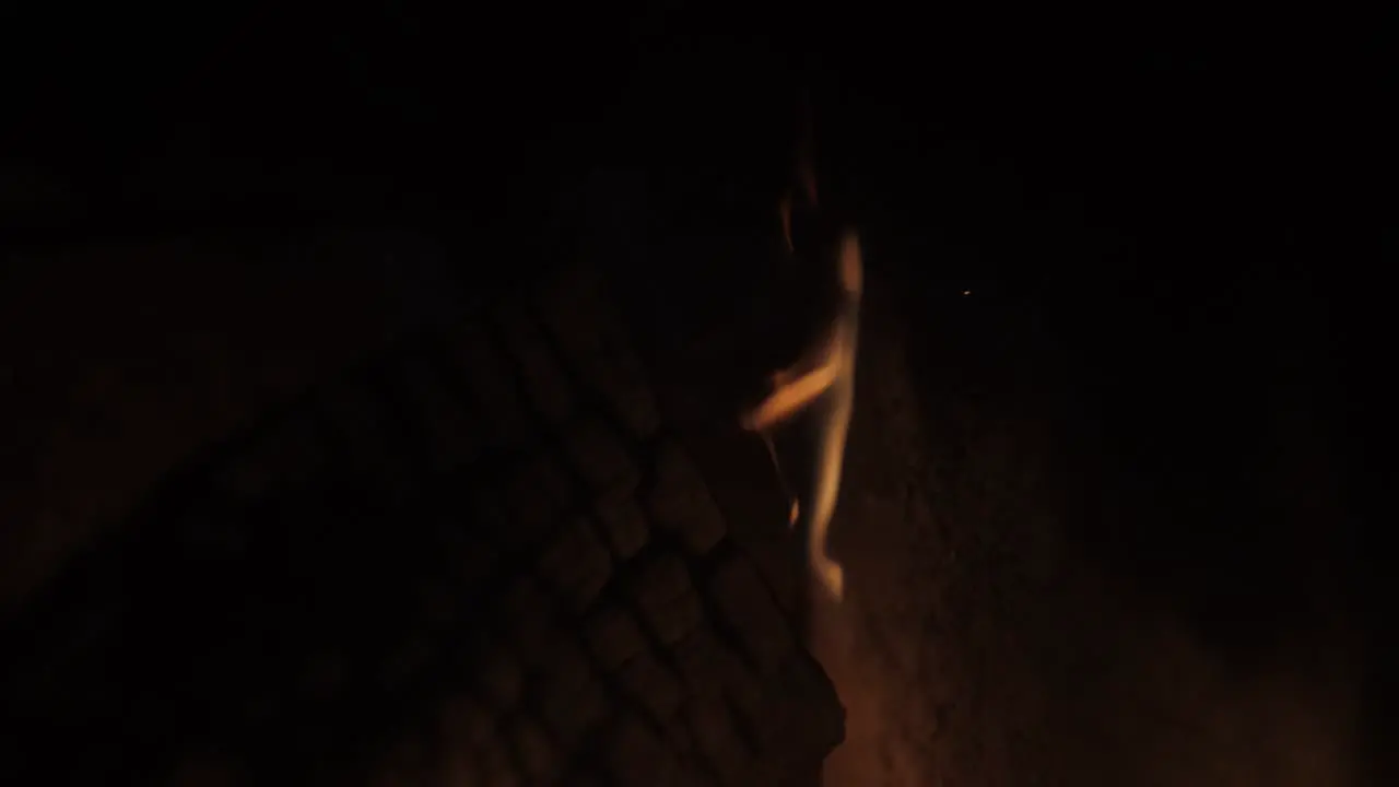 Fire in a fireplace in slow motion with pieces of wood through a tiled grill