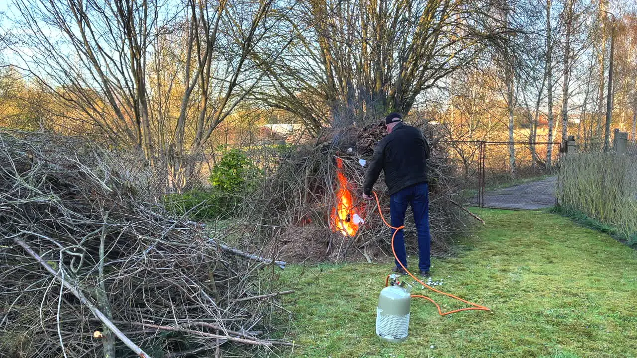 a man lights a big bonfire in a meadow