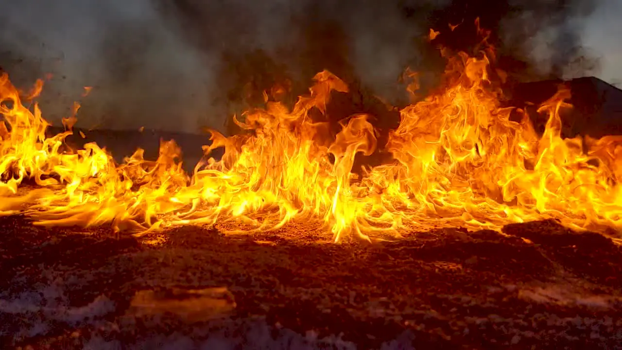 A wall of fire burns on the ground as an oil spill is dealt with in the field