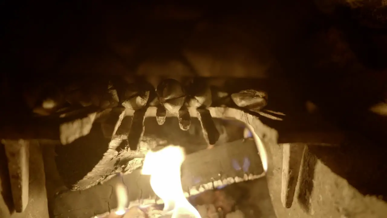 Flames gently burn two logs in a fireplace covered by an old grate in a remote bothy in Scotland