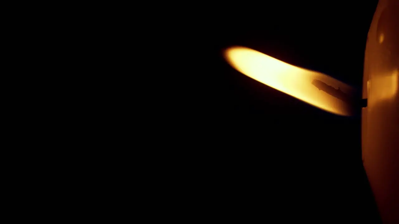 Vertical rotation of single big yellow candle flame lights isolated on a black background