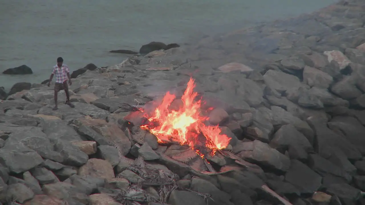 A man throws a piece of rubbish into a burning fire