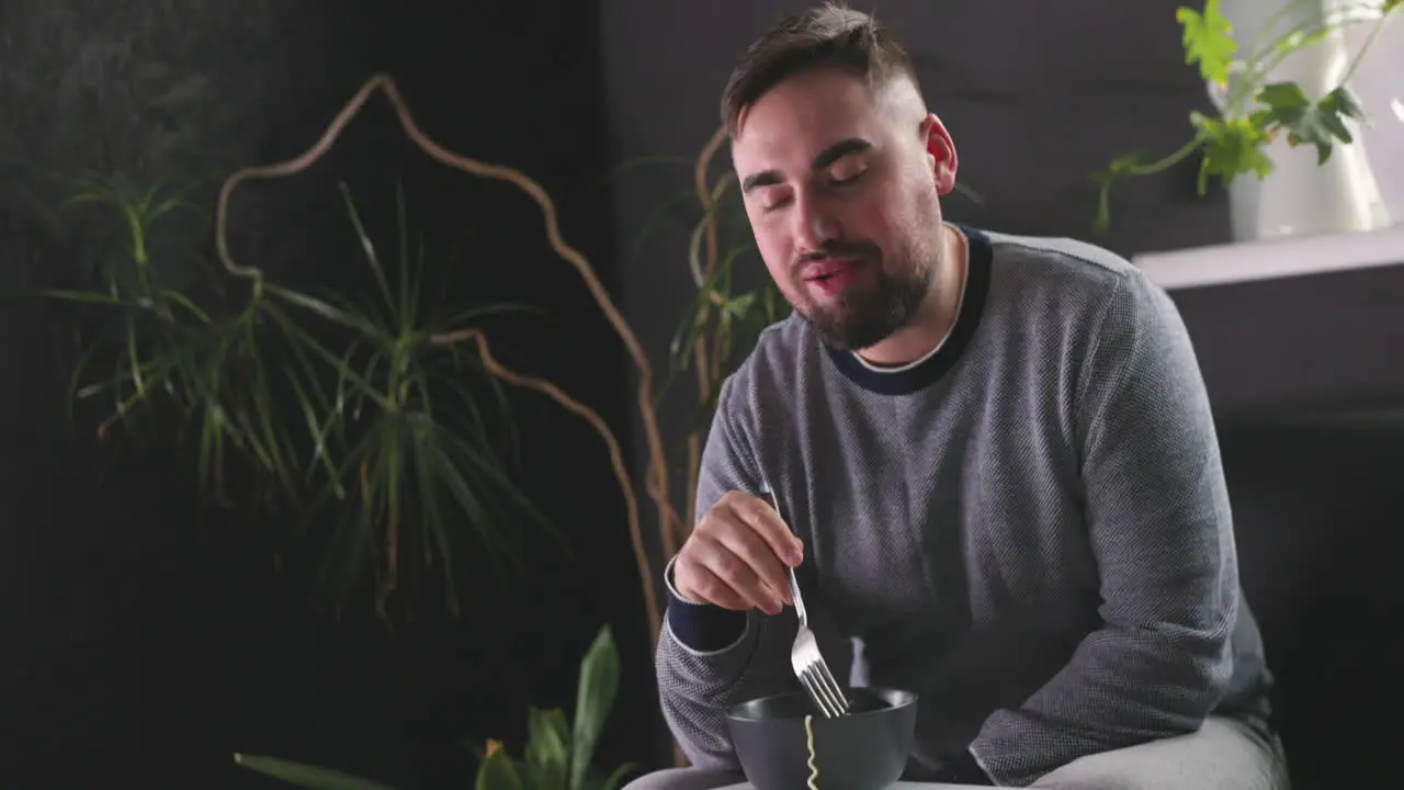 Hungry Man Sitting On Sofa And Eating Delicious Noodles