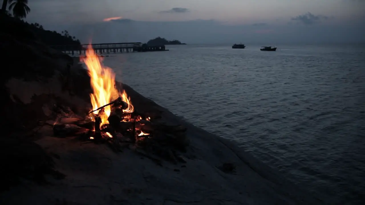 Camp fire on a hill of island with overview of sea during magic hour