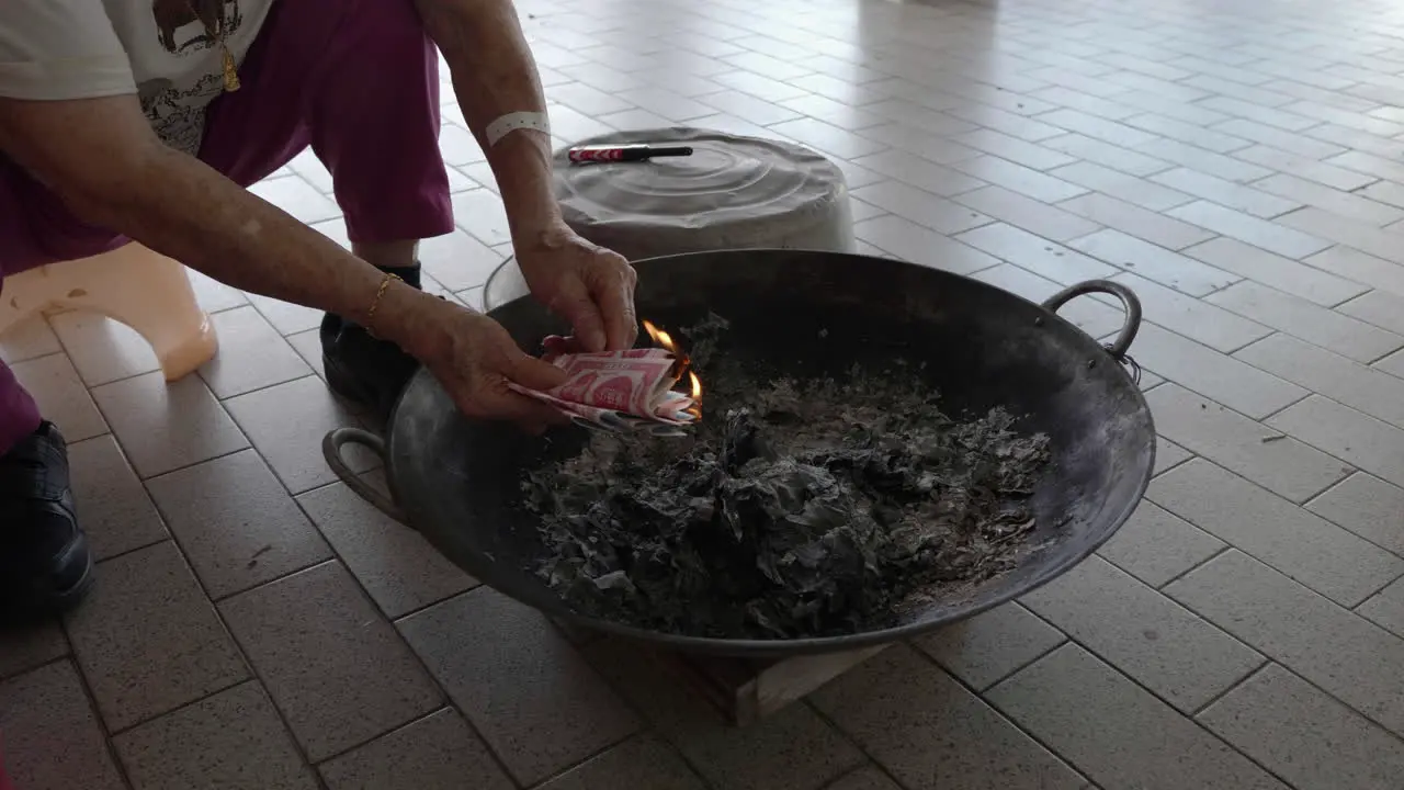 Medium shot put joss paper into the flame