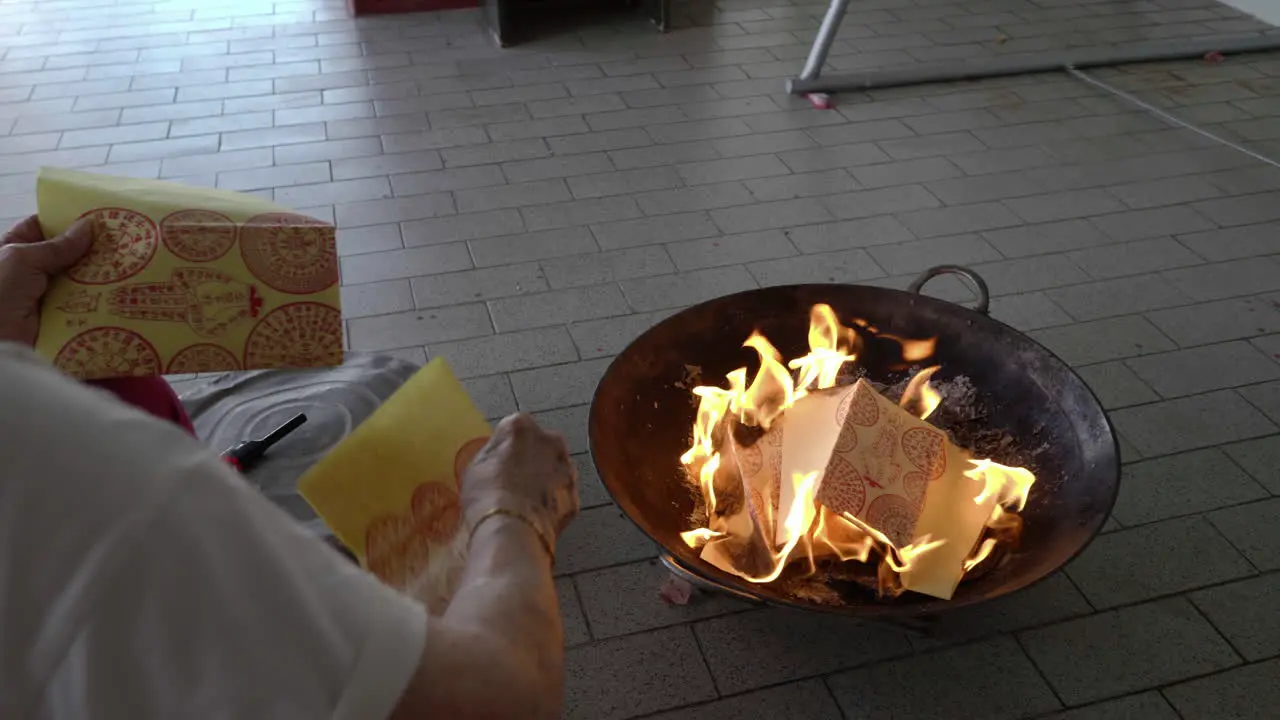 over-shoulder shot put joss paper into the flame