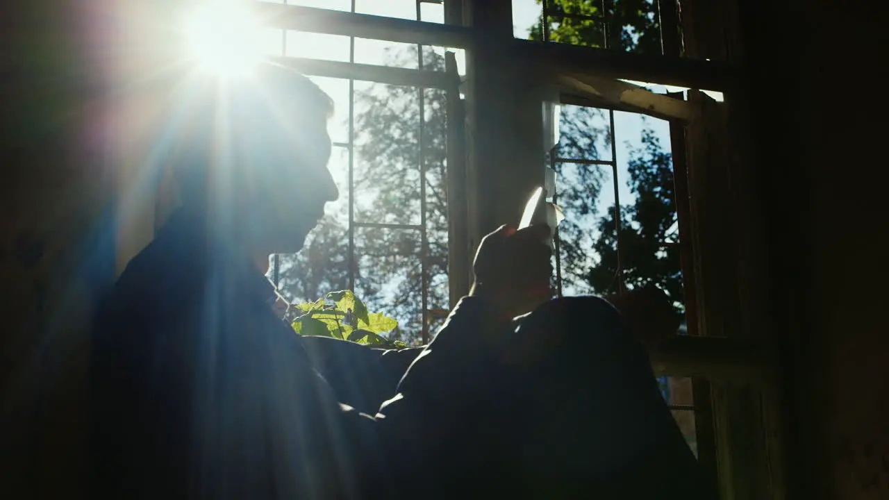 The Young Businessman In An Abandoned House He Sits On The Windowsill Uses A Telephone Silhouette In