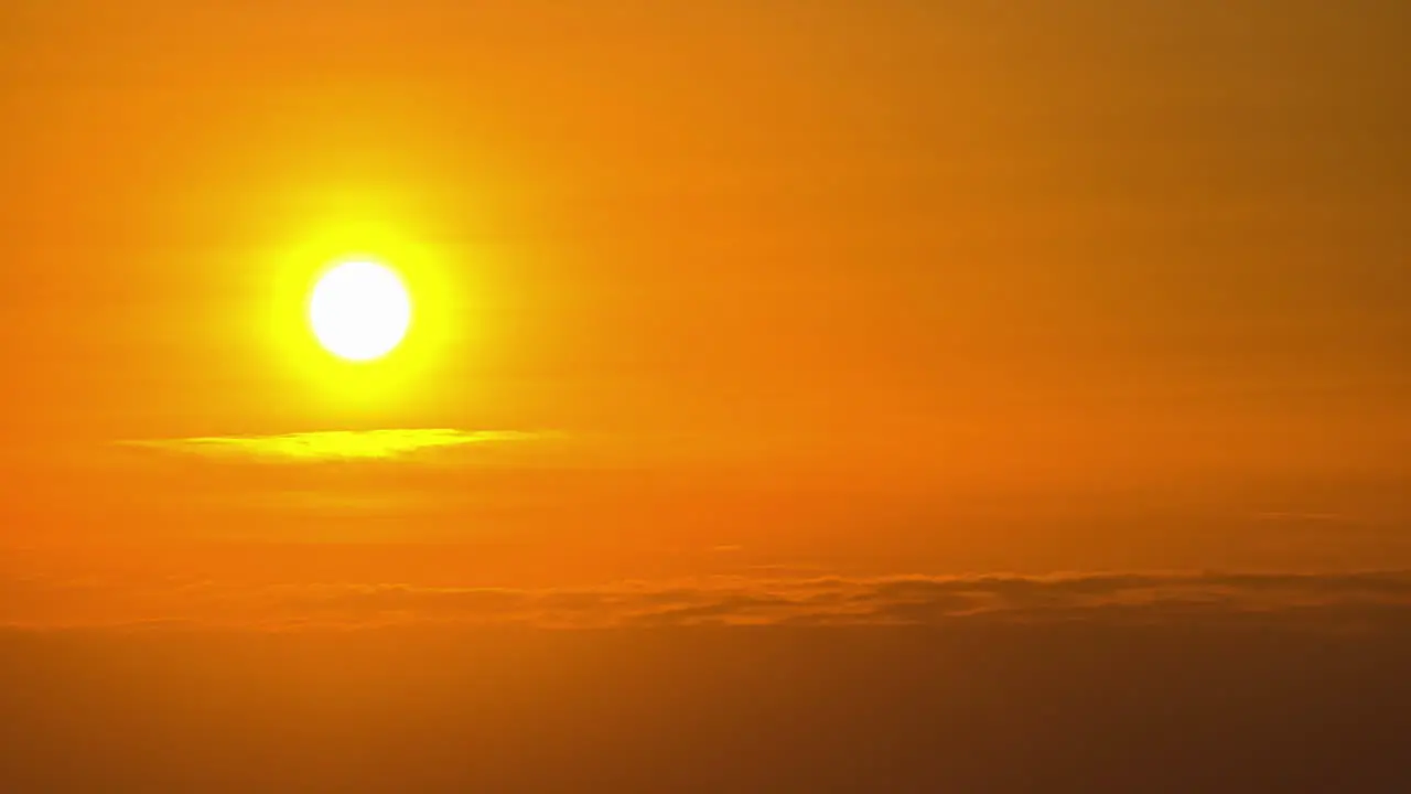 Bright fiery yellow sun as it descends through the sunset haze in a golden time lapse