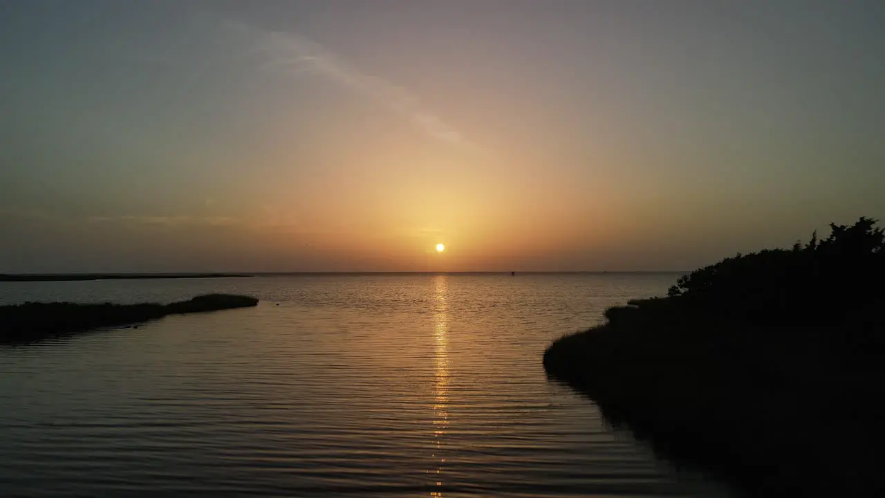 Sunset over bay with birds flying by