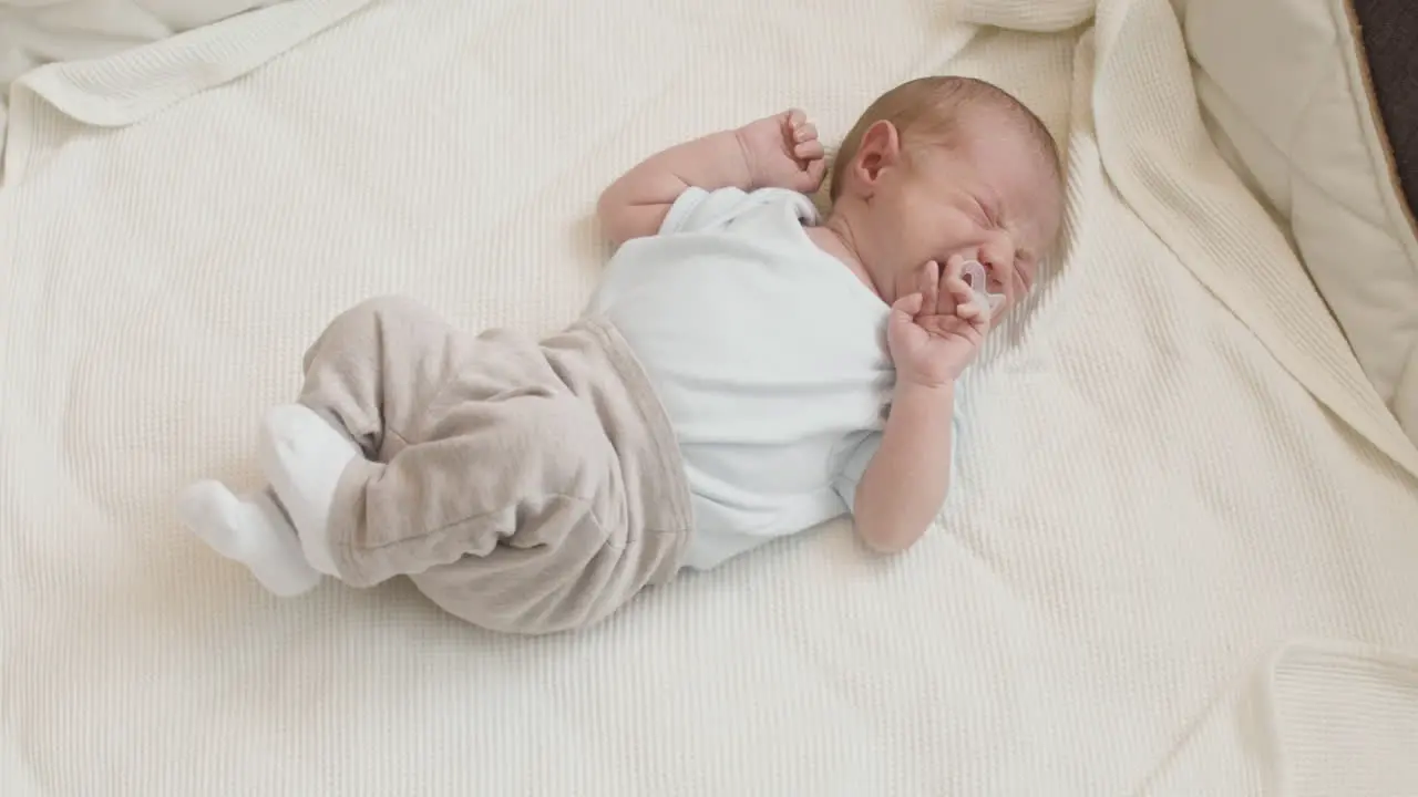 Cute Newborn Baby Lying On Bed And Crying