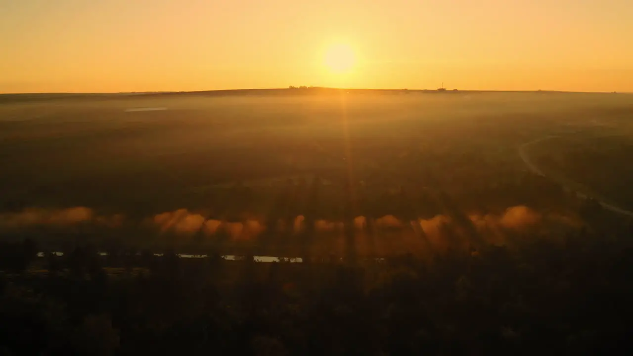 Landscape aerial drone shot of an amazing yellow sunrise over morning fog and clouds in Moldova countryside