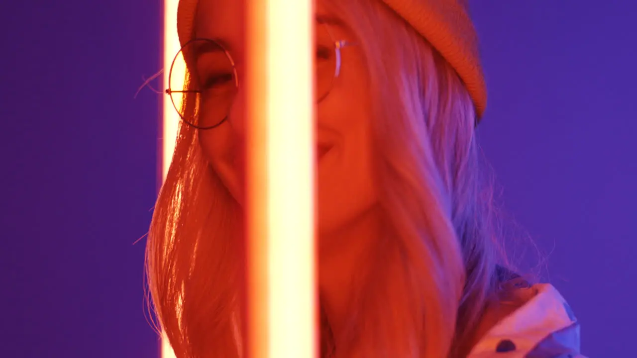 Close Up Of Young Blond Beautiful Woman In Hat And Glasses Smiling To The Camera With Neon Lamps Lights