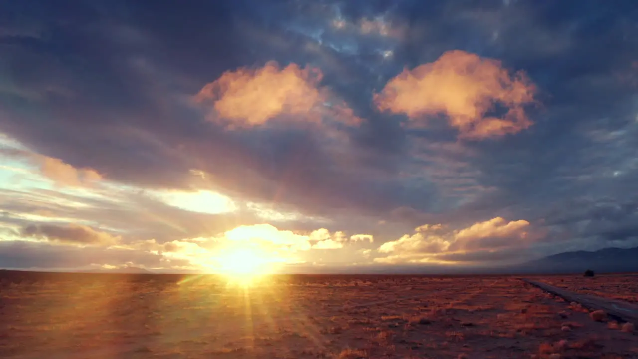 Bright golden sun with streaks rising over purple desert plain Tracking Left