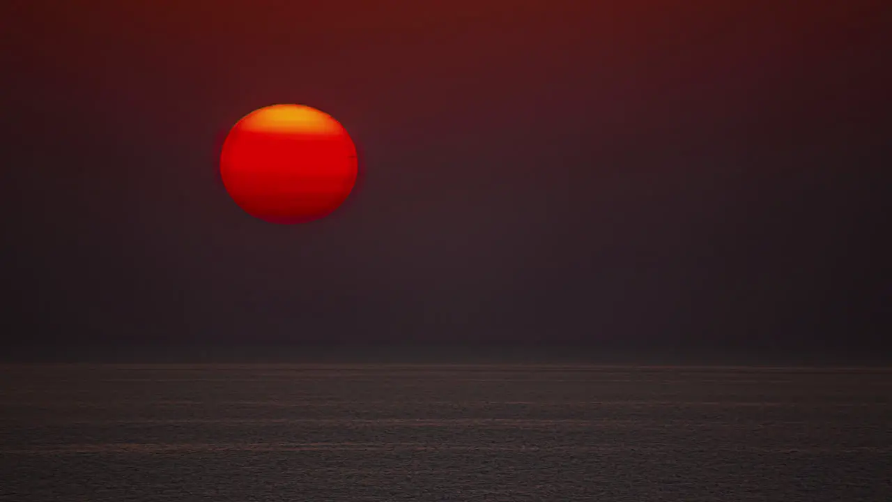 Timelapse shot of golden sunset going down behind ocean water at dusk in the evening close up