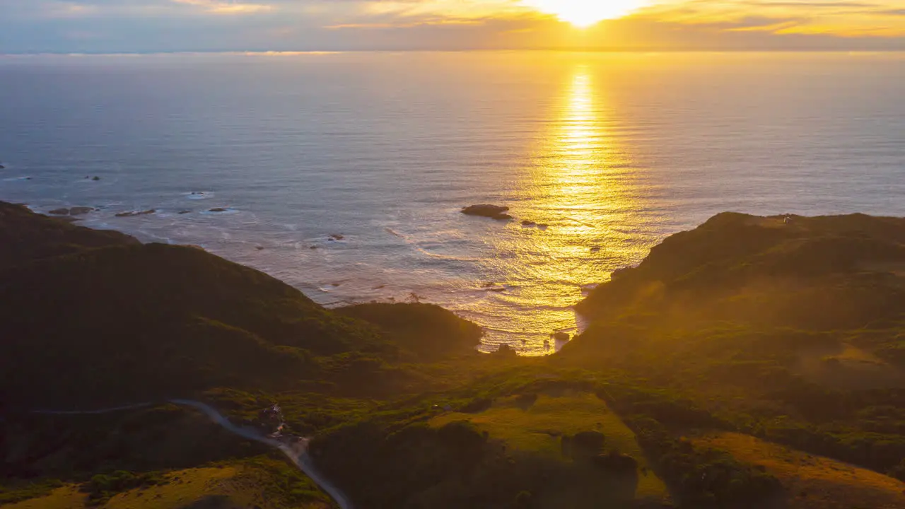 Aerial sweeping time-lapse of the sun setting over the Pacific Ocean showing the coastal countryside on the island of Chiloe beautiful sunset