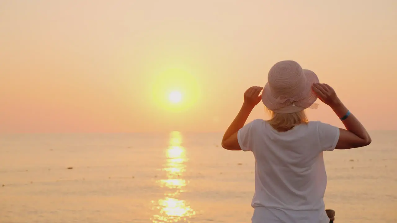 A Woman With A Hat In Her Hand Emotionally Meets The Dawn Over The Sea