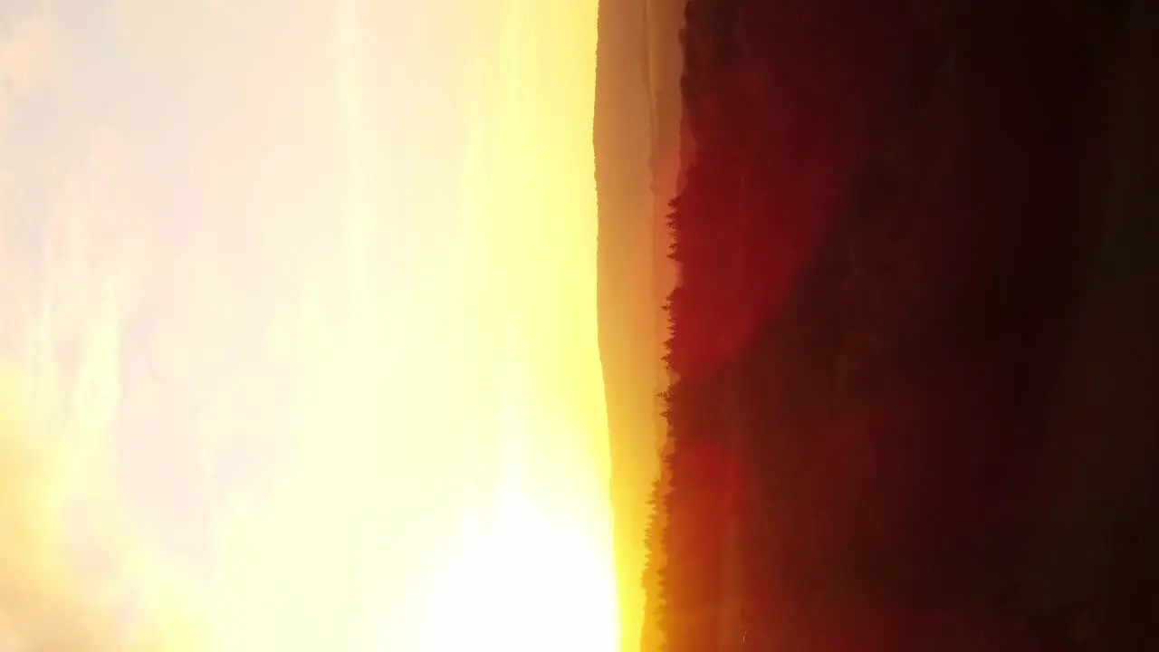 Vertical drone shot intense fiery sunset in nature over forests and fields