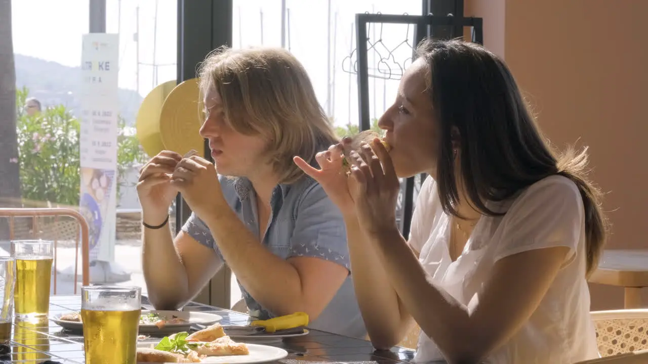 Young Man And Woman Eating Pizza At Restaurant