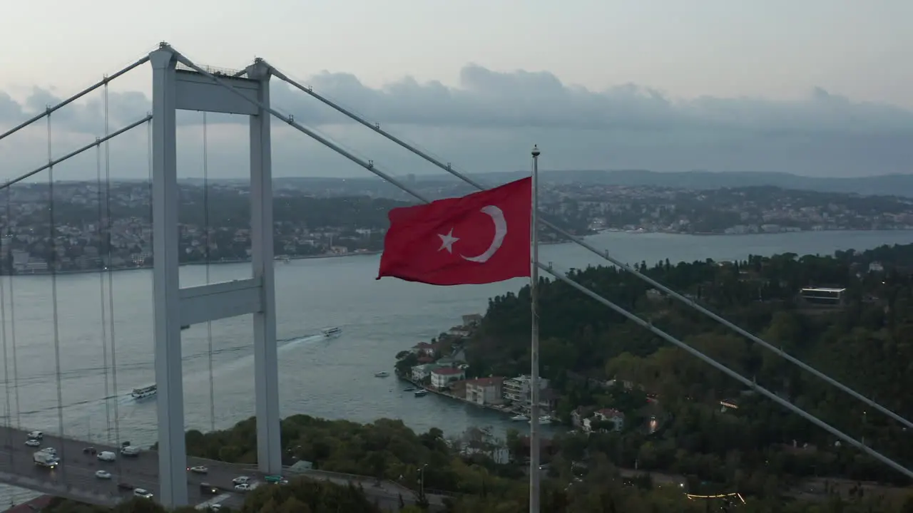 Turkish Flag Waving in Wind in front of Istanbul Bosphorus Bridge Aerial medium shot slide right