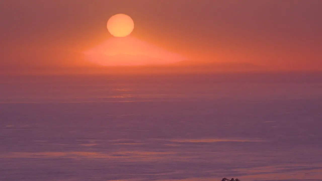 A Huge Red Round Ball Of Sun At Sunset Over The Pacific Ocean Near Malibu California