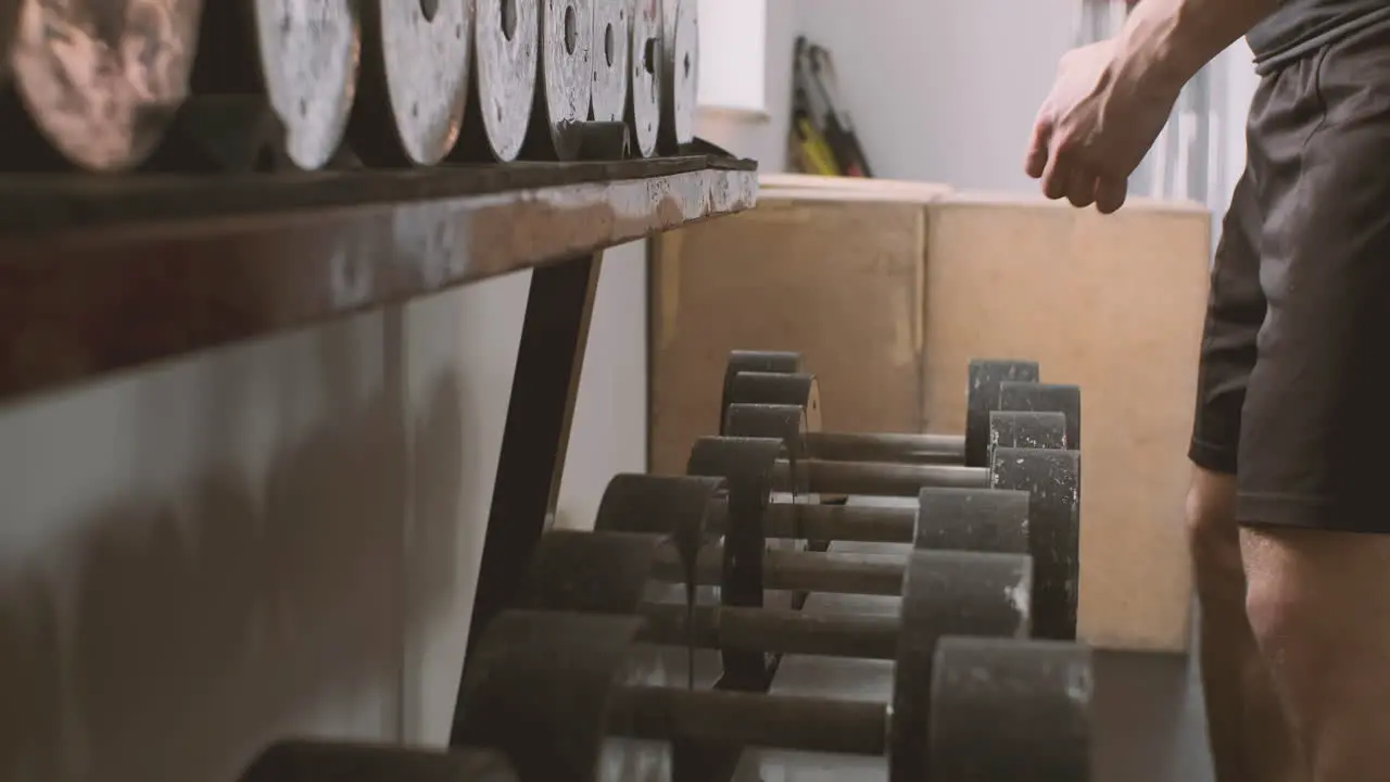 A Strong Man Picks Up A Pair Of Weights From A Row Of Dumbbells