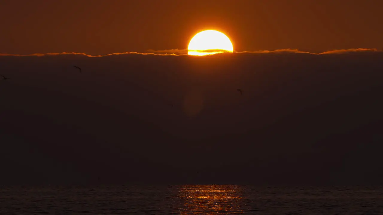 Sunrise over cloudy sky horizon time lapse of ball of red yellow warm sun over ocean sea coastline