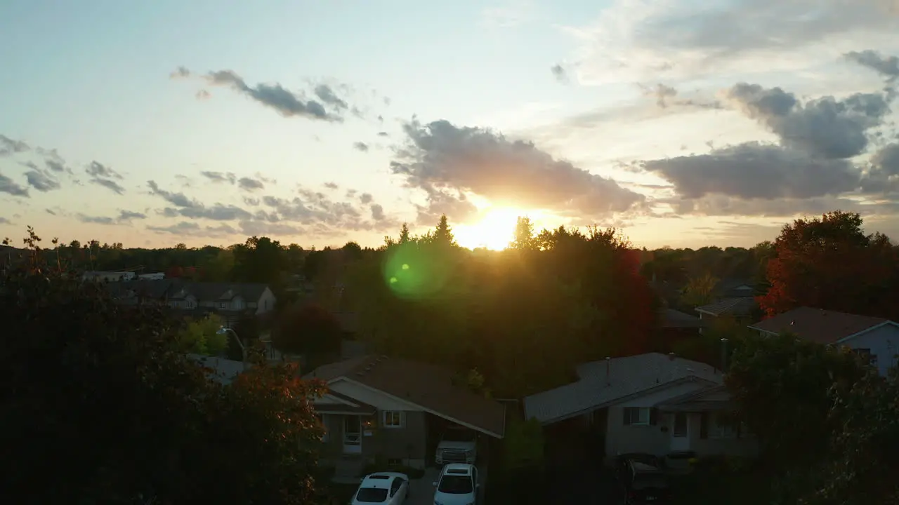 Drone aerial view ascending over the suburbs to reveal a sunset at dusk during autumn