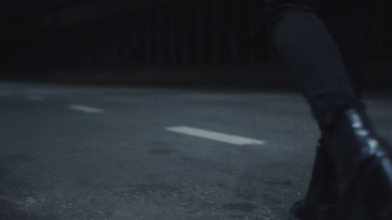 Female legs walking highway in black shoes or dark road with passing cars