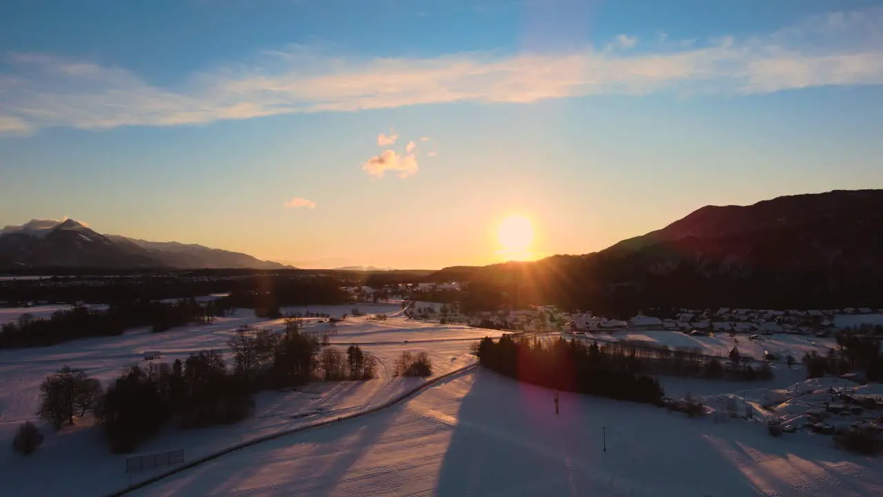 Drone shot of mountains fields and landscape in winter at golden hour sunrise with snow flying over hills and fields with vibrant colors