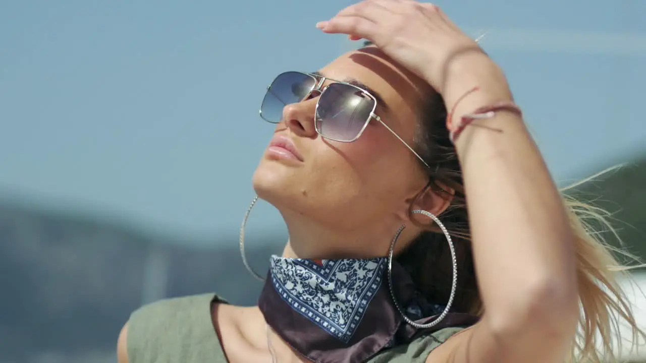 Young woman in sunglasses is looking towards the sun