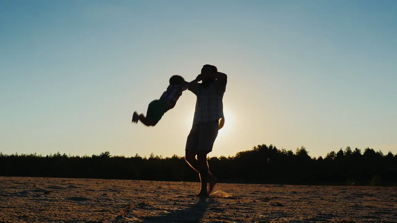 Healthy Father Playing With His Son At Sunset Circling It Beautiful Round Glare From The Sun In Th