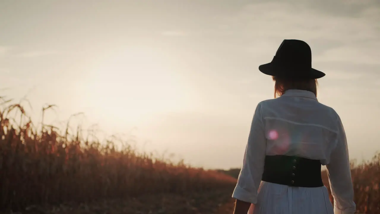 Farmer in a dress and hat walks in a field of ripe corn 4