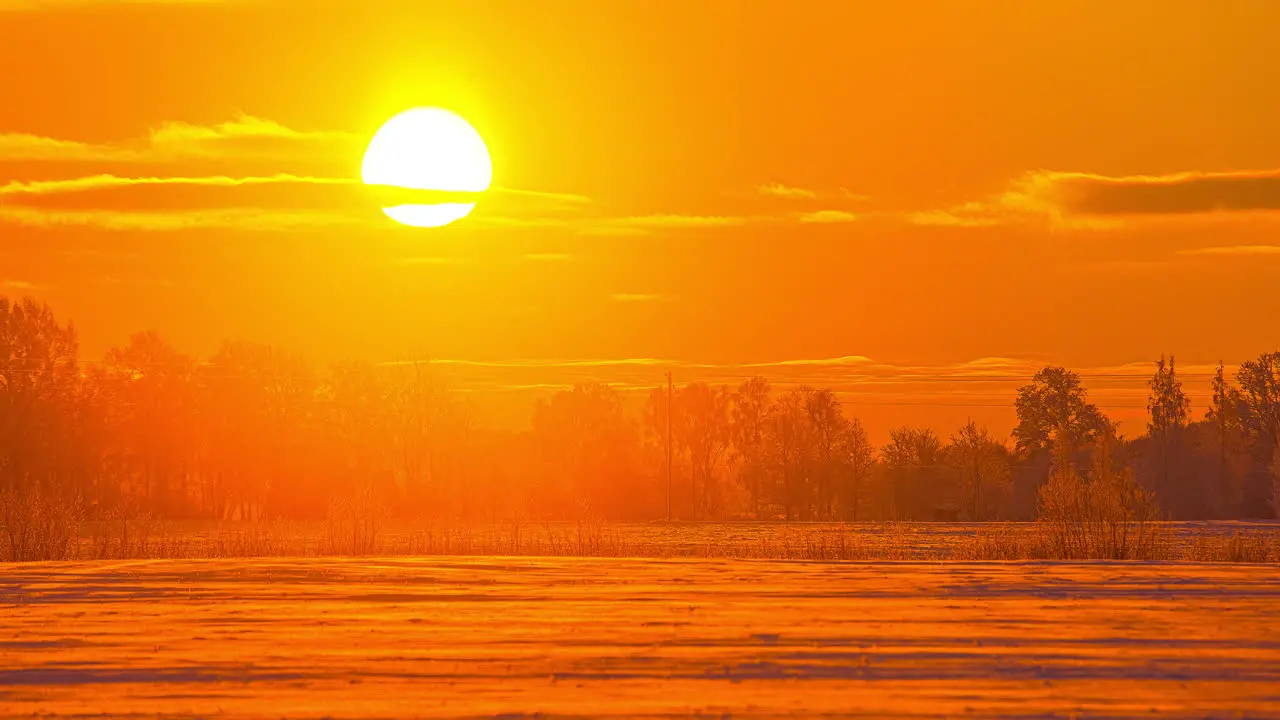 Time lapse shot of red burning sun rising up during snowy winter day with flying clouds at sky Picturesque snow landscape time-lapse in Nature