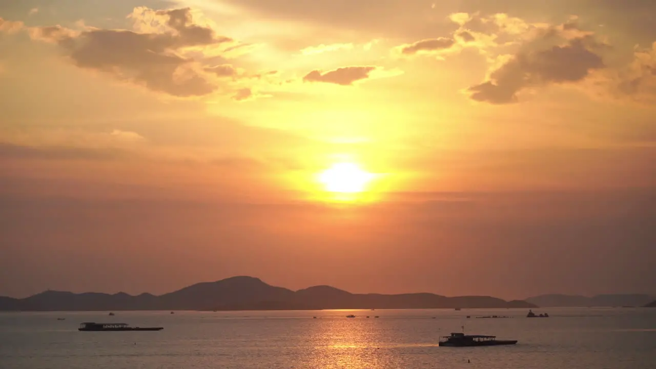 A golden orange sunset fills the sky over an idyllic seascape