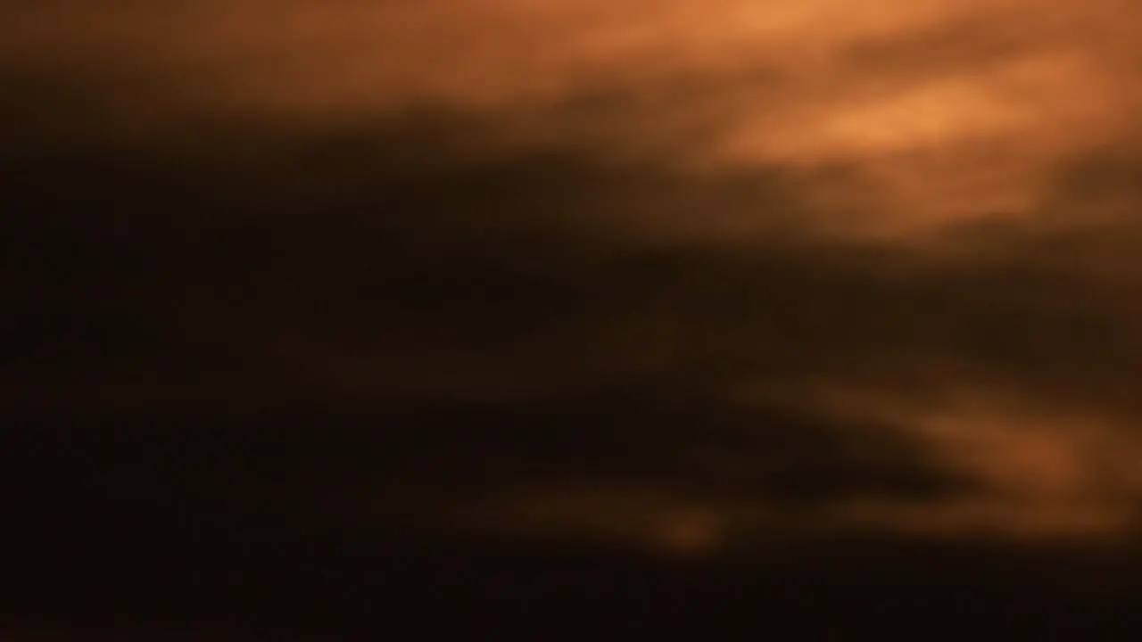 The blazing sun rising behind dark clouds time lapse