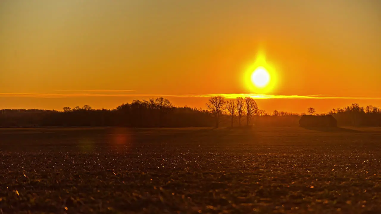 The golden sunrise breaks over the horizon and morning mist to illuminate the farmland fields time lapse