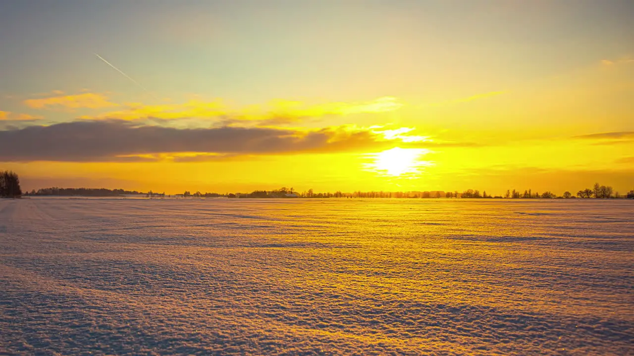 Beautiful vibrant orange time-lapse of sunset over snowy landscape