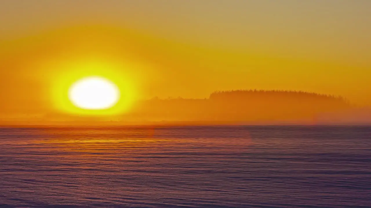 Time-lapse of vibrant colored setting sun over snowy landscape at sunset