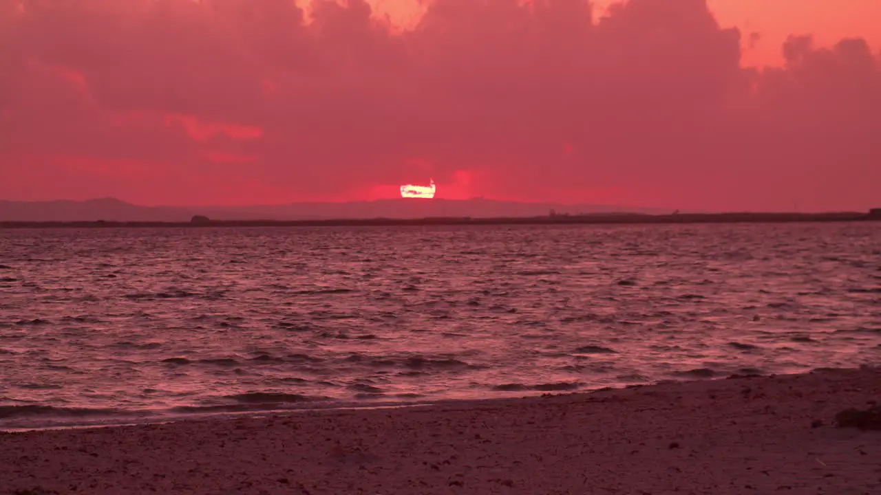 Astonishing pink sky sunset at sea beach waves crashing against sandy shore zoom in