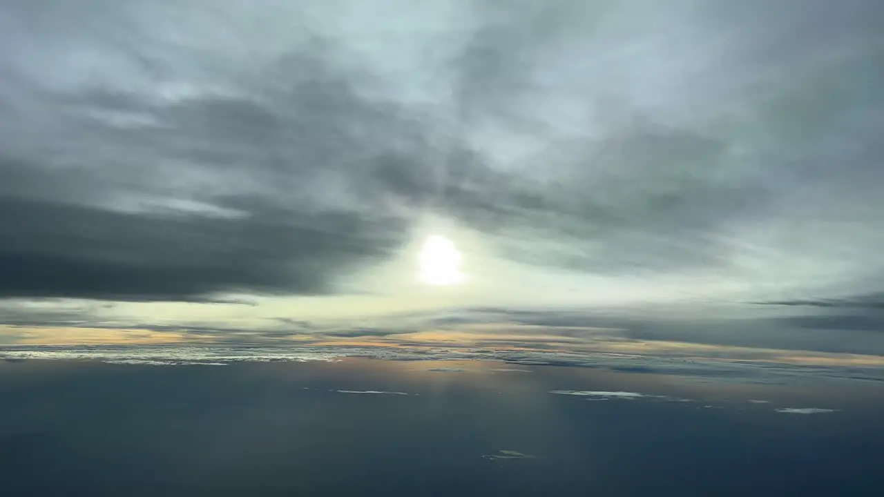 Aerial view from a jet cockpit in a cold winter afternoon before sunset at 12000 metres high with the sun vealed behind some clouds