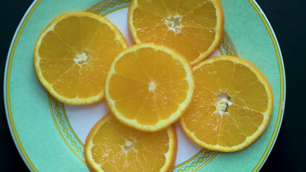 View from above of orange slices on a plate while the camera rotates