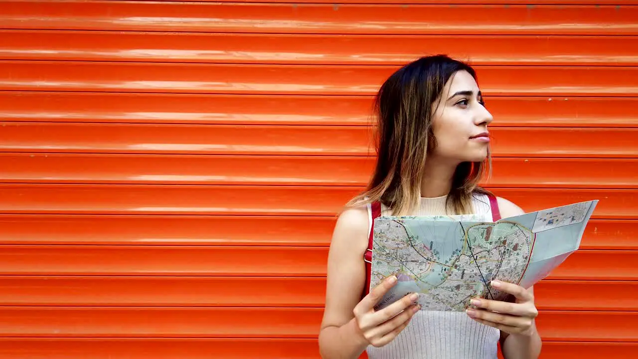 Slow MotionBeautiful young girl looks at map of Istanbul with orange red background