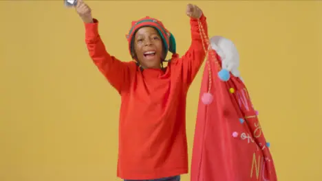 Happy Young Boy in Santa Hat Ringing Bell Holding Sack