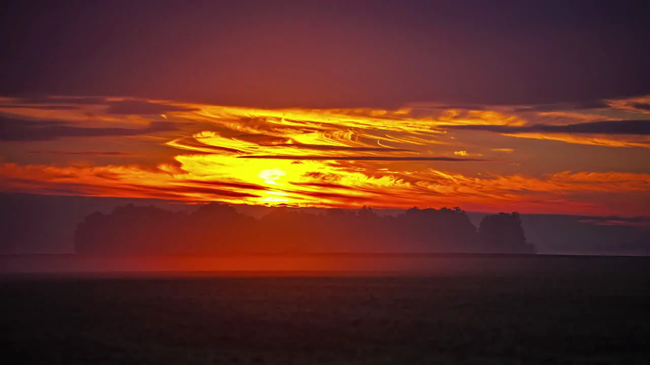 Golden sunrise as the wind blows in over a farmland field long duration time lapse