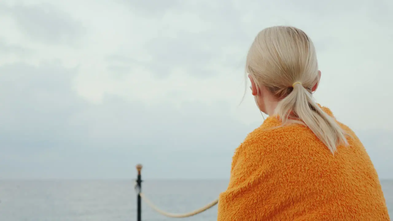 Dreamy Girl Sits On The Pier On A Cool Morning Rummages In A Blanket And Listens To Music On Headpho