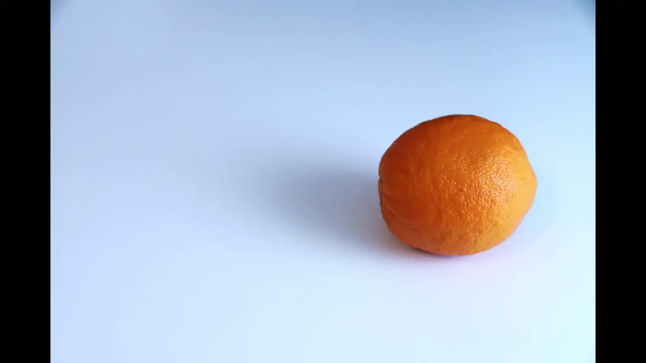 Whole orange fruit doing circles in stop motion isolated on white background