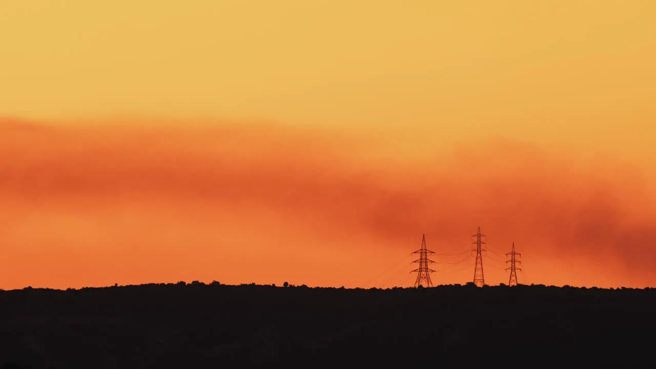 Misty golden dawn with smoke over electrical towers